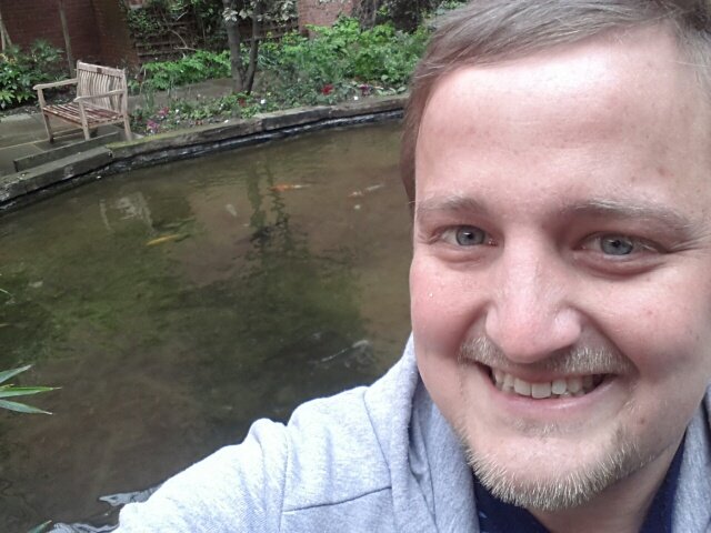 George in a hospital garden with a pond full of fish