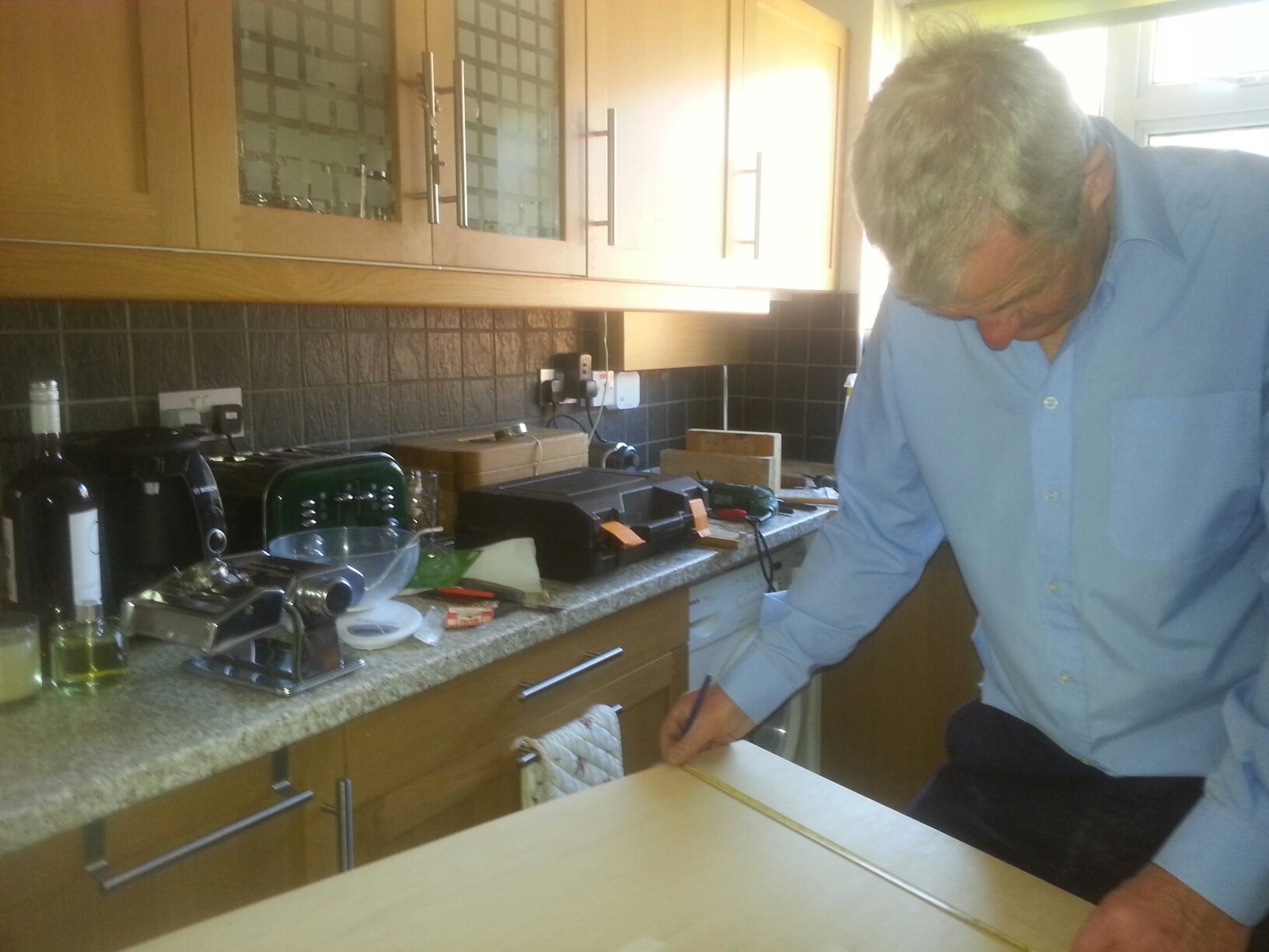 My father sawing some wood in the kitchen