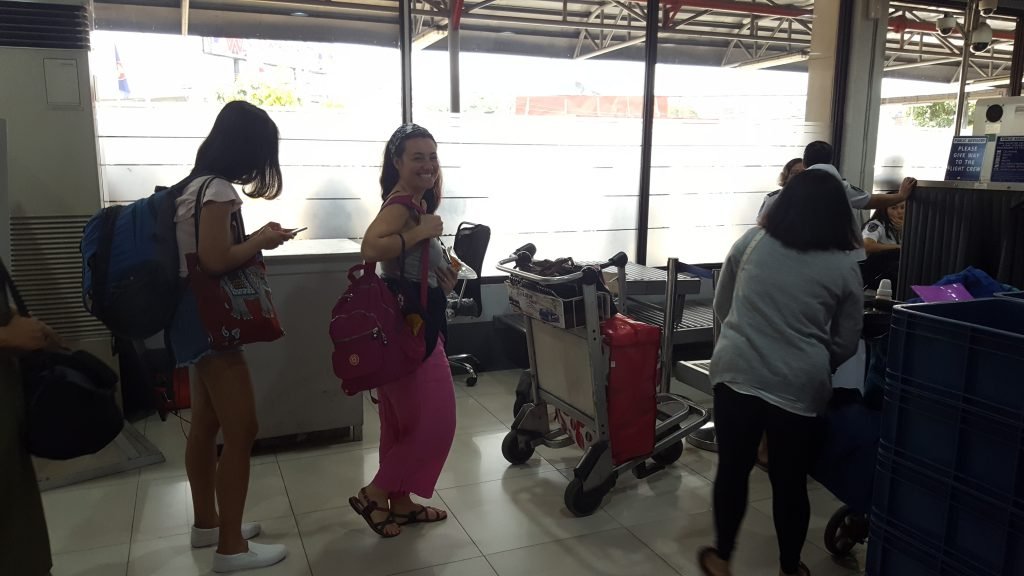 Mariacristina smiling as she carries hand luggage through security checks