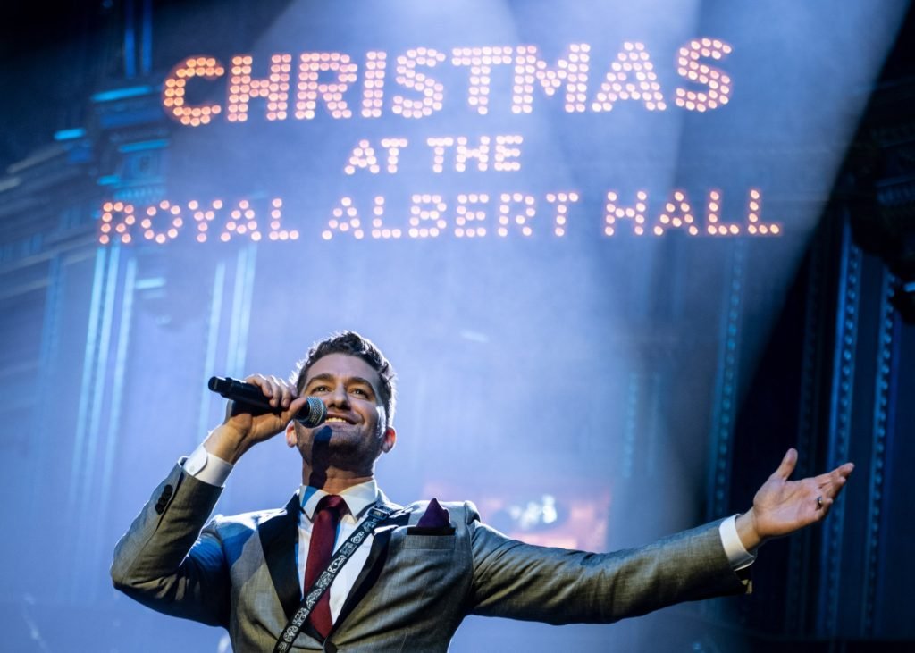 Glee actor/singer Matthew Morrison performing with CHRISTMAS AT THE ROYAL ALBERT HALL in lights behind him